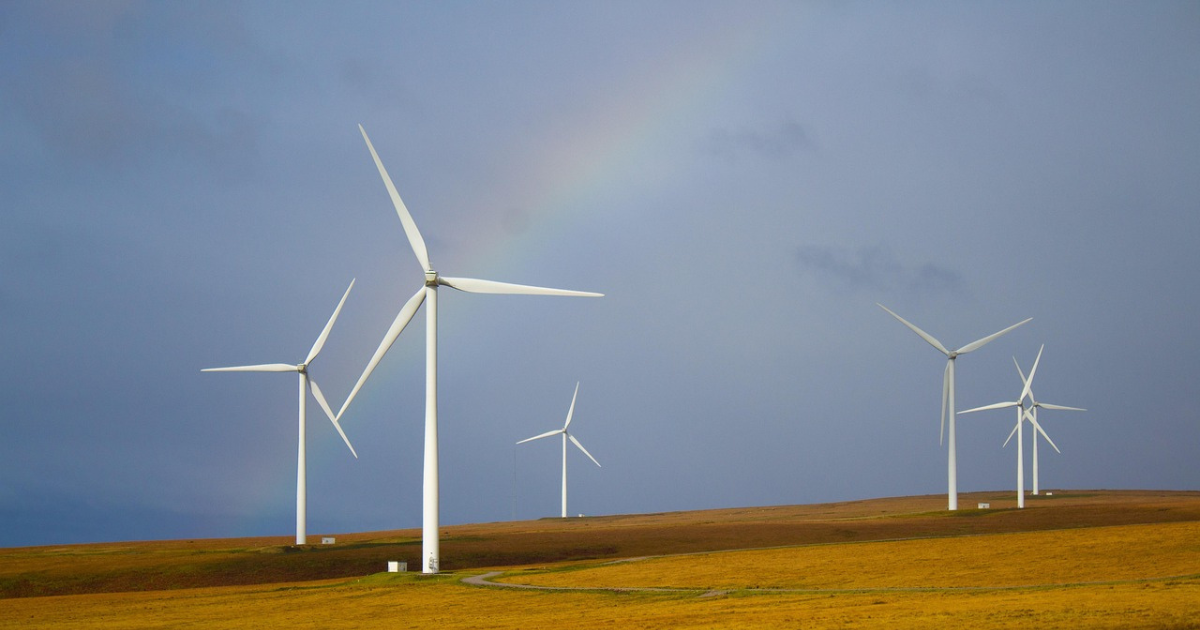 Wind turbines with a rainbow behind them